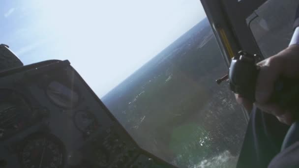 Zobrazit kontrolní systém pilot drží páku vrtulníku. Kamera v pilotní kabině. Nad zelený les. Slunečno — Stock video