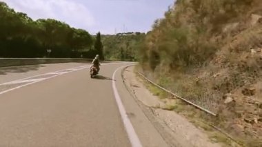 Dağlar yola motorla arka yüzünde iki kişi binmek. Birçok yeşil ağaçlar. Yaz güneşli gün
