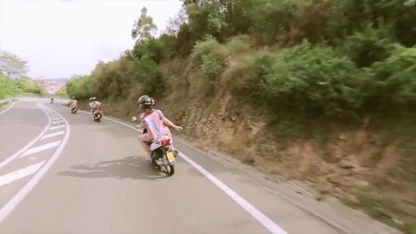 山で道路上のバイクに乗る人の裏側します。多くの緑の木々。夏の晴れた日. — ストック動画