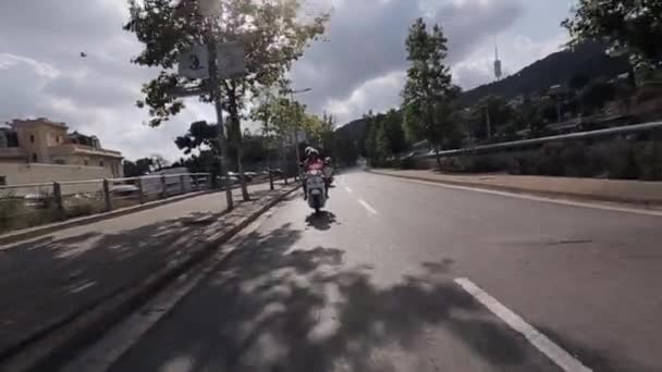 Le persone con vista frontale viaggiano in moto in città. Molti alberi verdi. Giornata estiva di sole. Mondo in viaggio — Video Stock
