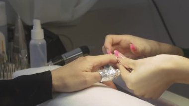 Profesyonel manikürcü güzellik salonda folyo ile kadın çivi sarar. Tırnak shellac kaldırma