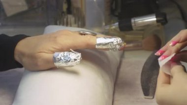 Manikürcü güzellik salonu kadının tırnakları üzerinde pamuk ped, sprey çözücü koydu. Tırnak shellac kaldırma