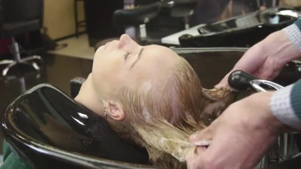 Professional barber rub in shampoo in hair of blonde young girl in beauty saloon. Massage of head — Stock Video