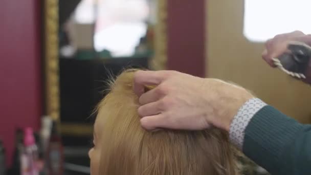 Professionell frisör kam toppen av hår till blond flicka i beauty saloon. Att göra volym frisyr. — Stockvideo