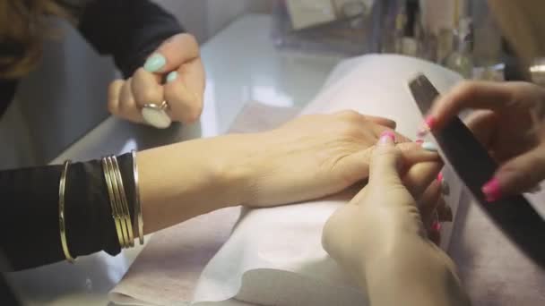 Manicurist plik dół górną pokrywę z gwoździ przez twardy plik paznokci w salonie piękności. Usuwanie lakieru do paznokci — Wideo stockowe