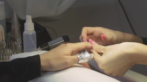 La manicura profesional envuelve las uñas de la mujer por la laminilla en el salón de belleza. Extracción de goma laca de uñas — Vídeo de stock