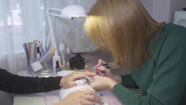 Manicurista esmalte superficie de las uñas a la mujer atractiva por aparato de uñas. Manicura de hardware — Vídeos de Stock