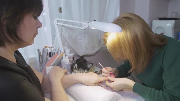 Επαγγελματική manicurist τεθεί εκτός basic από την επιφάνεια των νυχιών του πελάτη στο σαλόνι ομορφιάς από πορτοκαλί ραβδί — Αρχείο Βίντεο