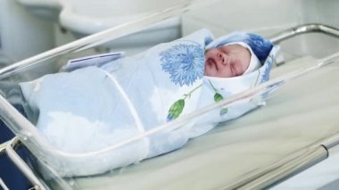Yeni doğan bebek giysili kafa, hareketli mavi battaniye annelik hastanede yatıyordu. Şeffaf kutu