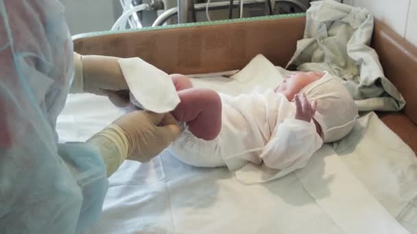 Enfermera poner en calcetín desechable pie izquierdo del bebé recién nacido llorando después del nacimiento. Hospital de maternidad . — Vídeo de stock