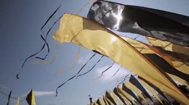 Siyah ve sarı bayraklarıyla gelen rüzgar yaz güneşli bir günde sallayarak bantlar. Festivali. Mavi bulutsuz gökyüzü