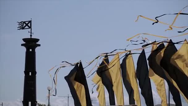 Черные и желтые ленты на флагах одного цвета, махающие ветром в летний день. Чёрная колонна с флагом — стоковое видео