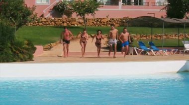 Beş genç insan çalıştırmak ve Yüzme Havuzu tek tek atlamak. Yaz güneşli gün. Tatil. Splash