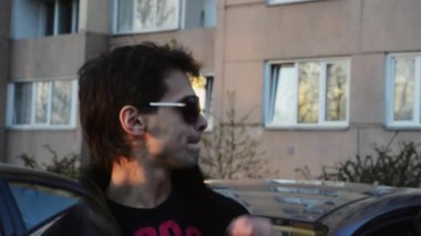 Güneş gözlüklü esmer adam rap kamera yaz akşamları sokağa okuyun. Siyah ceket. Sanatçı