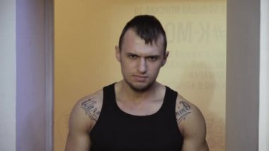 Omuz dövme ile siyah tişörtlü ciddi sakallı kas genç adam kamera görünüyor. Thews