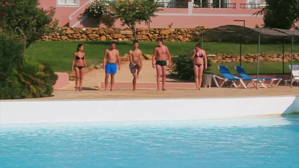 Cinco jóvenes se calientan, hacen ejercicios en la piscina delantera. Día soleado de verano. Vacaciones — Vídeos de Stock