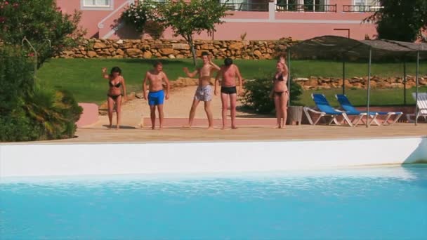Cinco jóvenes saludan con las manos en la cámara frente a la piscina. Día soleado de verano. Vacaciones. Temblores — Vídeos de Stock