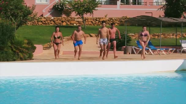 Cinq jeunes courent et sautent ensemble dans la piscine. Journée ensoleillée d'été. Des vacances. Splash ! — Video