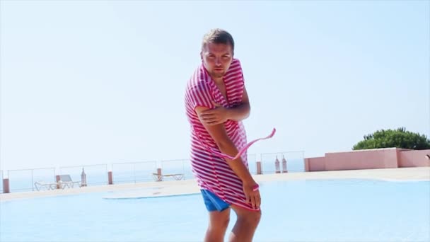 Hombre en túnicas rosadas sexy posando mirada en la cámara. en la piscina. Viento. Día soleado de verano. Cielo azul — Vídeo de stock