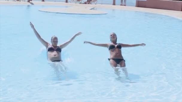 Dos niñas caen todo el peso en la espalda en la piscina. Día soleado de verano. Vacaciones. Salpicadura — Vídeos de Stock