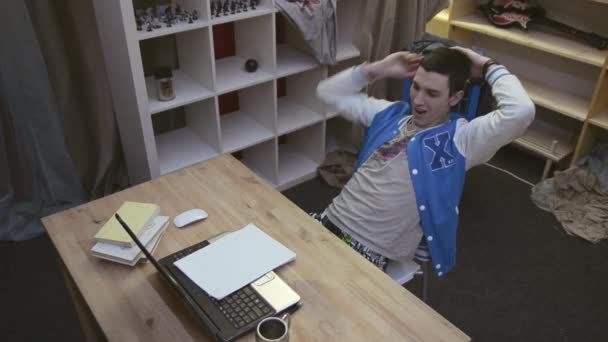 Jeune garçon brune bâillant, estomac égratigné sur la chaise dans le carnet avant. Souris. Étudiant. Adolescent 