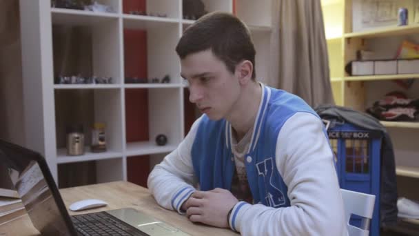 Jonge jongen in blauw sport jas geeuwen vooraan scherm van de laptop in de kamer. Slaperig. Touch oor. Moe — Stockvideo