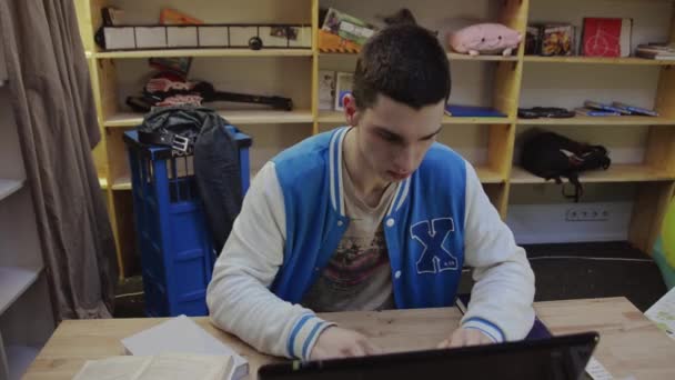 Niño tocando en el teclado de la libreta en la mesa. Alguien le lanza papeles. Concentración — Vídeo de stock