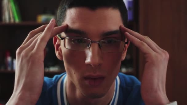 Ritratto di giovane ragazzo in occhiali sguardo serio sullo schermo. Faccia il massaggio di tempio. Studente. La noia . — Video Stock