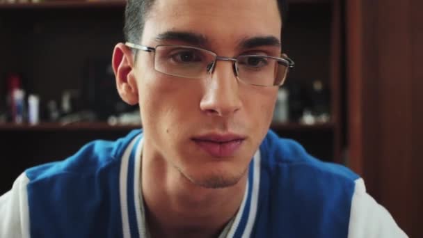 Portrait of brunette boy in glasses serious look in screen. Look around. Say some words. Student. — Stock Video