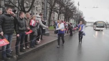 SAINT PETERSBURG, RUSSIA - OCTOBER 27, 2013: Running man in uniform give pompons to people. Relay race of Sochi Olympic flame in Saint Petersburg