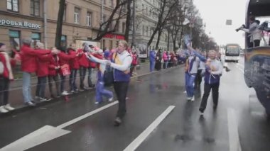 SAINT PETERSBURG, RUSSIA - OCTOBER 27, 2013: Walking people, youth wave pompons, jump. Relay race of Sochi Olympic flame in Saint Petersburg