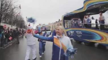 SAINT PETERSBURG, RUSSIA - OCTOBER 27, 2013: People give five to torchbearer, wave pompons. Relay race of Sochi Olympic flame in Saint Petersburg