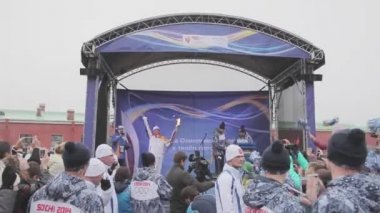Saint Petersburg, Rusya - 27 Ekim 2013: bayrak yarışı Sochi Olimpiyat Meşalesi, Saint Petersburg. Alev ile sahnede ışık tutan kimse. Dalga eller