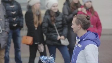 SAINT PETERSBURG, RUSSIA - OCTOBER 27, 2013: Walking boy volunteer give pom pom to teens. Relay race of Sochi Olympic flame in Saint Petersburg