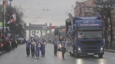 SAINT PETERSBURG, RUSSIA - OCTOBER 27, 2013: Walking volunteers wave pom pom. Bus. Relay race of Sochi Olympic flame in Saint Petersburg
