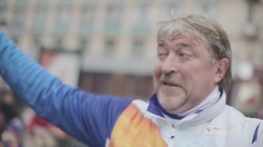 Saint Petersburg, Rusya - 27 Ekim 2013: Yaşlı adam dalga ponpon, yetişkin kadın verin. St. Petersburg'da Soçi Olimpiyat meşalesi bayrak yarışı