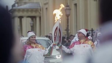 Saint Petersburg, Rusya - 27 Ekim 2013: Ekim ayında St. Petersburg'da bayrak yarışı Olimpiyat ateşi. Yetişkin meşale taşıyıcısı kadına alev geçmek