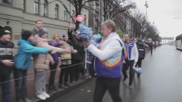 SAINT PETERSBURG, RUSSIA - OCTOBER 27, 2013: Walking old man in uniform give pompon to people. Relay race Sochi Olympic flame in Saint Petersburg — Stockvideo