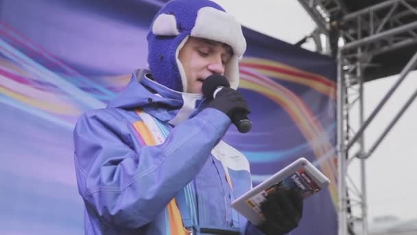 SAINT PETERSBURG, RUSSIE - 27 OCTOBRE 2013 : Jeune homme hôte en veste violette, chapeau chaud avec microphone lire le texte sur tablette sur scène. Concert . — Video