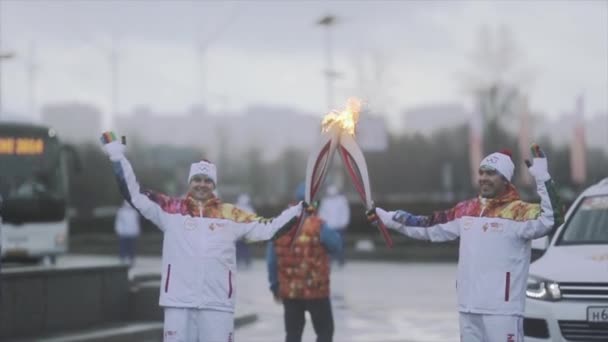 SAINT PETERSBURG, RÚSSIA - 27 de outubro de 2013: Corrida de revezamento Sochi tocha olímpica em São Petersburgo. Dois portadores de tochas acenam as mãos. Momento passar chama — Vídeo de Stock