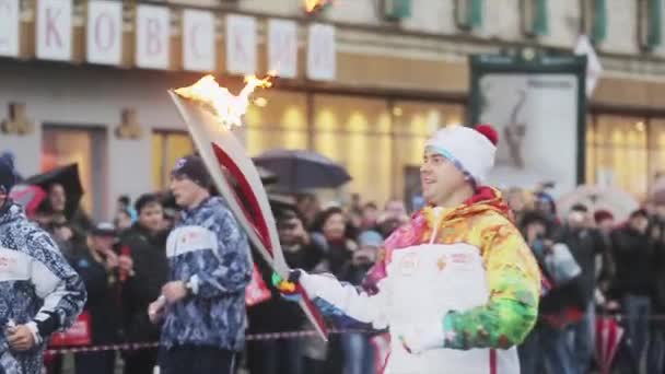 Sint-Petersburg, Rusland - 27 oktober 2013: estafette Sotsji Olympische toorts in Sint-Petersburg. Running mannelijke fakkeldrager vlam doorgeven aan vrouw. — Stockvideo