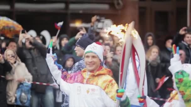 SAN PETERSBURG, RUSIA - 27 DE OCTUBRE DE 2013: Carrera de relevos Sochi Antorcha olímpica en San Petersburgo. El portador de la antorcha pasa llama. Posando en cámara. Sonríe — Vídeos de Stock