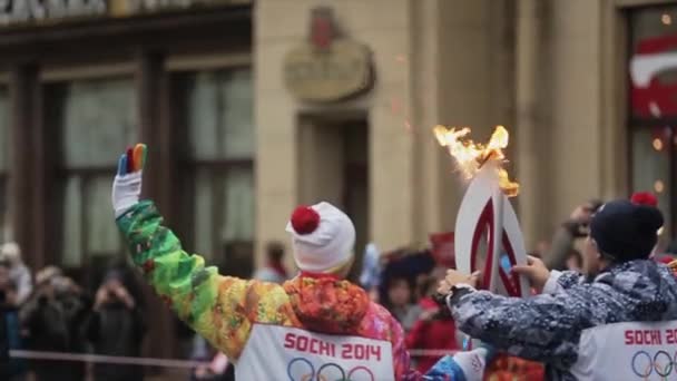 SAINT PETERSBURG, RÚSSIA - 27 de outubro de 2013: Corrida de revezamento Sochi tocha olímpica em São Petersburgo. Torchbearer lateral traseiro passar chama. Dose na câmara — Vídeo de Stock