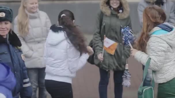 SAINT PETERSBURG, RUSSIA - OCTOBER 27, 2013: Walking boy volunteer give pom pom to girls. Relay race of Sochi Olympic flame in Saint Petersburg — Wideo stockowe