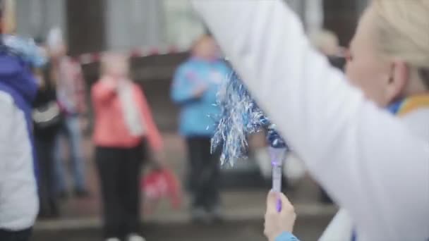 SAN PETERSBURG, RUSIA - 27 DE OCTUBRE DE 2013: Jovencita sacudiendo pom pom, sonrisa en cámara. Carrera de relevos de la llama olímpica de Sochi en San Petersburgo — Vídeos de Stock