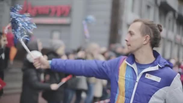 SAN PETERSBURG, RUSIA - 27 DE OCTUBRE DE 2013: Un joven le regala pompones a una chica, suéltala. Carrera de relevos de la llama olímpica de Sochi en San Petersburgo — Vídeo de stock