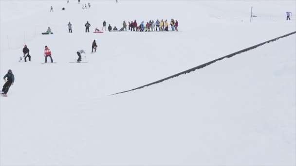 Snowboarder rijden op helling-stap-springen op de trampoline in de besneeuwde berg. Wedstrijd. Uitdaging. Mensen — Stockvideo