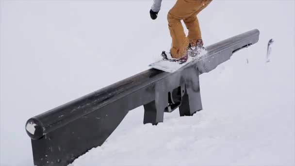 Сноубордист прыгает по железной тропе в снежной горе. Каскадёры. Конкурс. Вызов. Крайне. Горнолыжный курорт — стоковое видео