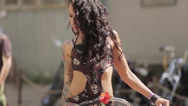 Moskou, Rusland-27 juli 2015: sexy donker haar Tattoo meisje in zwarte badpak poseren op geschilderde groene fiets. Zonnige dag in de zomer. — Stockvideo