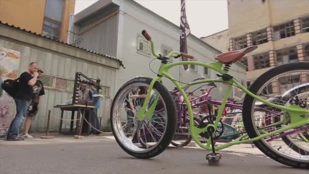 МОСКВА, РОССИЯ - 27 июля 2015 года: Зеленый велосипед с различными колесами стоит на улице в одном ряду с другими. Выставка. Солнечный летний день — стоковое видео